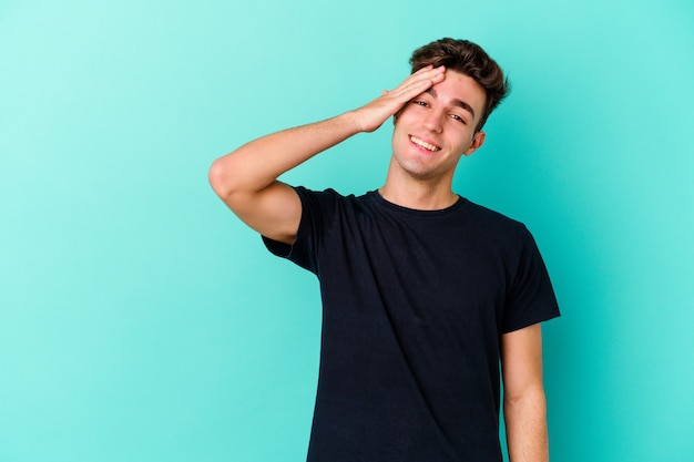 Jeune homme caucasien isolé sur un mur bleu en riant une émotion naturelle, insouciante et heureuse.