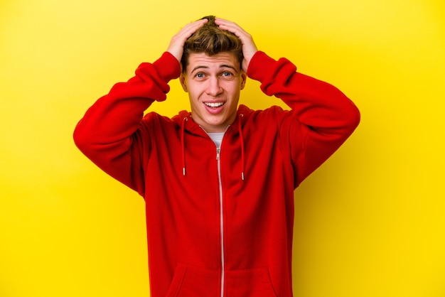 Jeune homme caucasien isolé sur un mur jaune hurlant, très excité, passionné, satisfait de quelque chose.