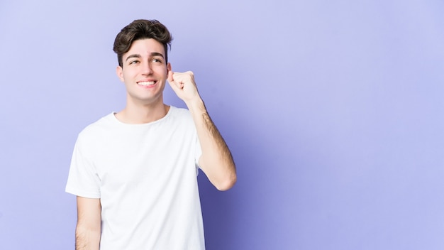 Jeune homme caucasien isolé sur un mur violet célébrant une victoire, une passion et un enthousiasme, une expression heureuse.