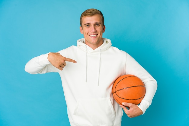 Jeune homme caucasien jouant au basket isolé sur fond bleu se mordant les ongles, nerveux et très anxieux.