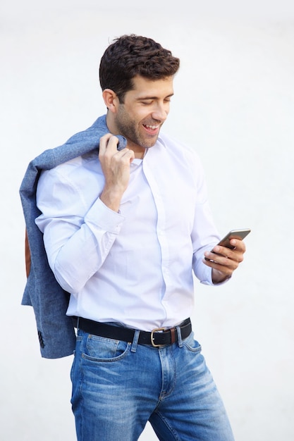 Un jeune homme caucasien lisant un message sur son téléphone portable sur un fond blanc.
