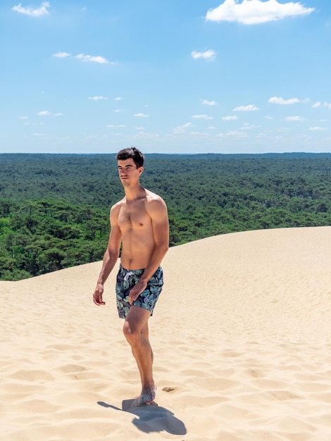 Jeune homme caucasien marchant dans la dune du pilat