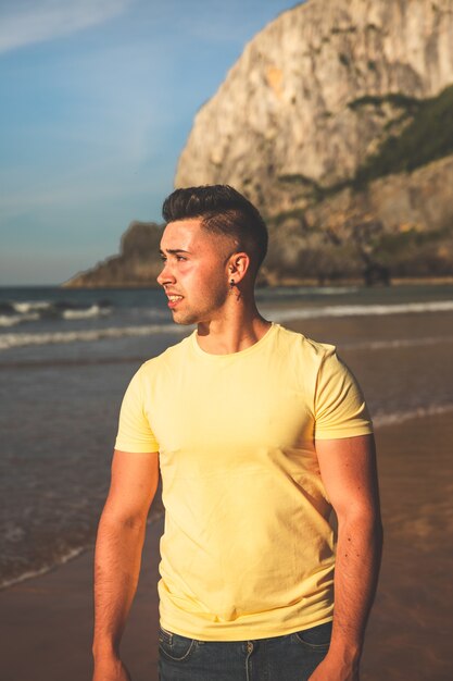 Jeune homme caucasien marchant à la plage