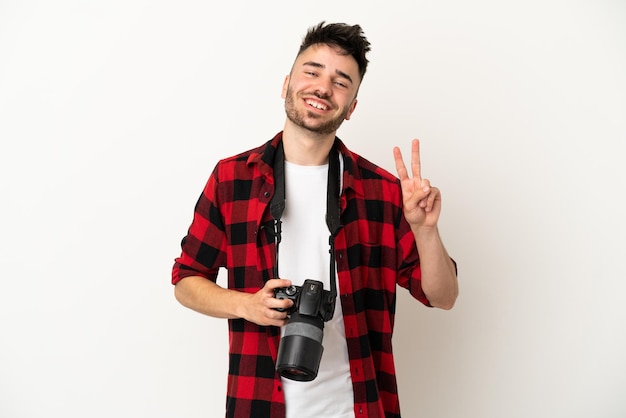 Jeune Homme Caucasien De Photographe Isolé Sur Fond Blanc Souriant Et Montrant Le Signe De La Victoire