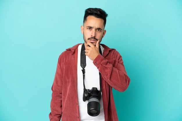 Jeune homme caucasien photographe isolé sur fond bleu surpris et choqué en regardant à droite