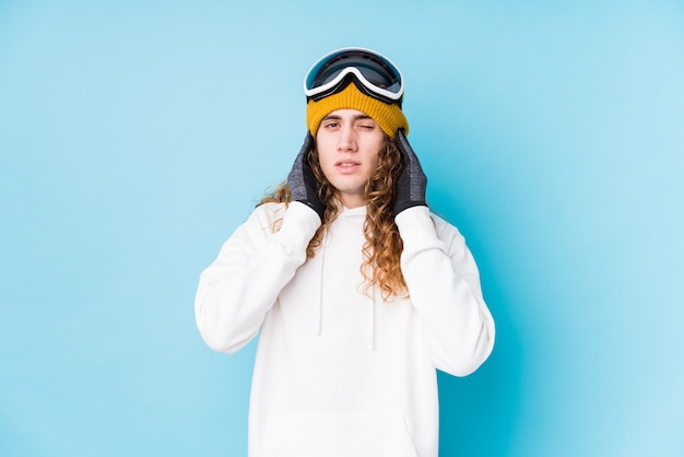 Jeune homme caucasien portant un vêtement de ski isolé couvrant les oreilles avec les mains.