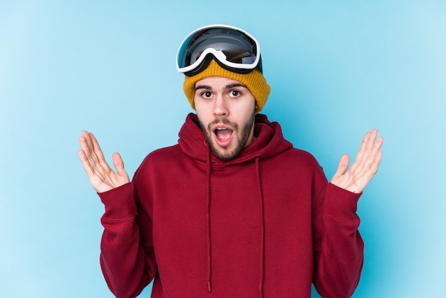 Jeune homme caucasien portant un vêtement de ski surpris et choqué.