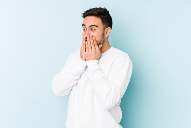 Jeune homme caucasien riant de quelque chose, couvrant la bouche avec les mains.