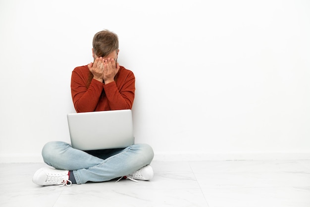 Jeune homme caucasien rougeâtre avec ordinateur portable isolé sur fond blanc avec une expression fatiguée et malade