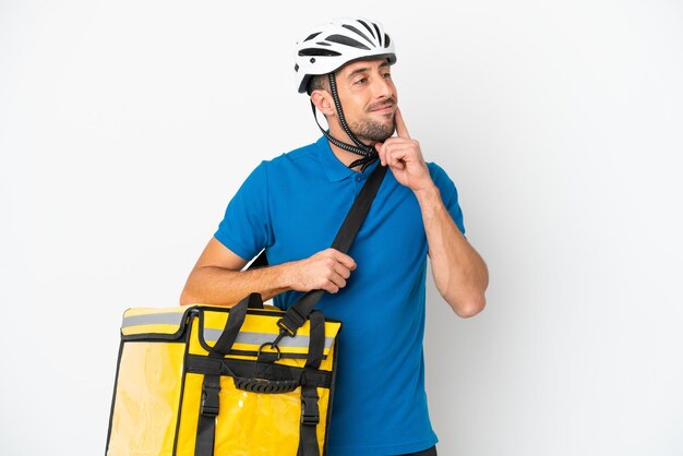 Jeune homme caucasien avec sac à dos thermique isolé sur fond blanc en pensant à une idée tout en levant les yeux