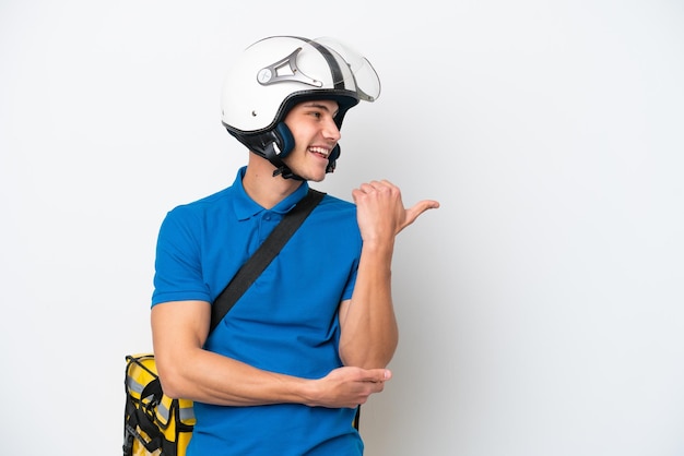 Jeune homme caucasien avec sac à dos thermique isolé sur fond blanc pointant vers le côté pour présenter un produit