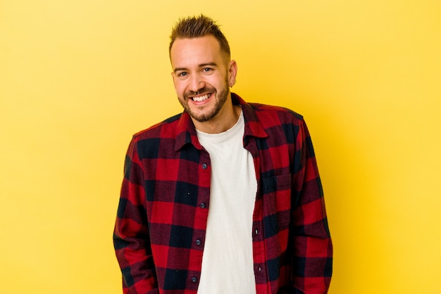 Jeune homme caucasien tatoué isolé sur fond jaune heureux, souriant et joyeux.