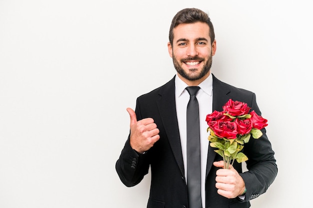 Jeune homme caucasien tenant un bouquet de fleurs isolé sur fond blanc souriant et levant le pouce vers le haut