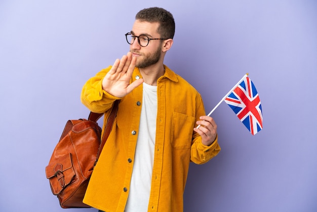 Jeune homme caucasien tenant un drapeau du Royaume-Uni isolé