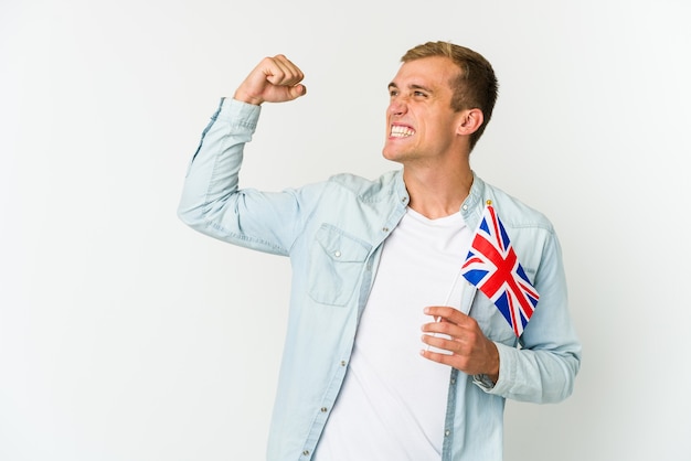 Jeune homme caucasien tenant un drapeau du Royaume-Uni sur le poing blanc après une victoire, concept gagnant.