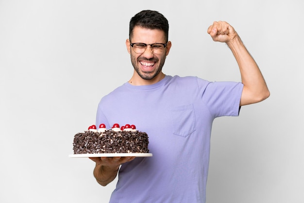 Jeune homme caucasien tenant un gâteau d'anniversaire isolé sur fond blanc faisant un geste fort