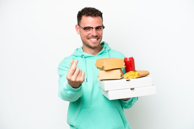 Jeune homme caucasien tenant restauration rapide isolé sur fond blanc faisant un geste d'argent