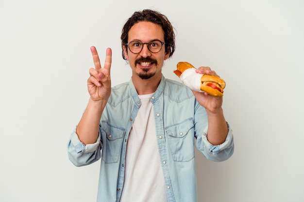 Jeune homme caucasien tenant un sandwich isolé sur blanc montrant le numéro deux avec les doigts.