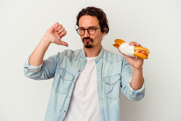 Jeune homme caucasien tenant un sandwich isolé sur fond blanc se sent fier et confiant, exemple à suivre.