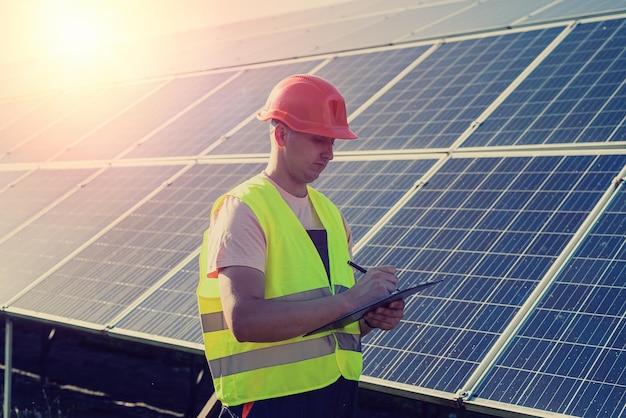 Jeune homme caucasien en uniforme travaille dans une station solaire Concept d'énergie verte