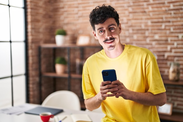 Jeune homme caucasien utilisant un smartphone debout à la maison