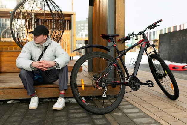 Un jeune homme caucasien avec une veste grise et une casquette noire a loué un vélo