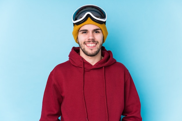 Jeune homme caucasien vêtu d'un vêtement de ski isolé heureux, souriant et joyeux.