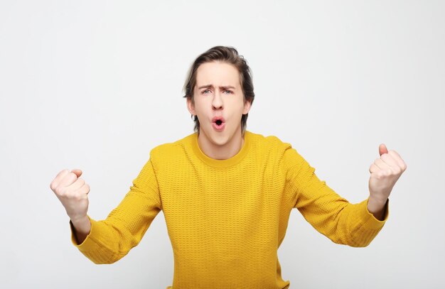 jeune homme célébrant la victoire sur fond blanc