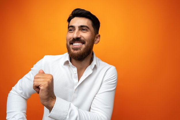 Un jeune homme célèbre et danse sur un fond orange dans un studio.