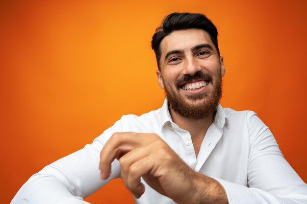 Un jeune homme célèbre et danse sur un fond orange dans un studio.