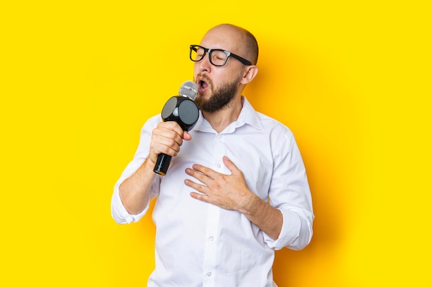 Jeune homme chantant aux yeux fermés avec un microphone sur fond jaune