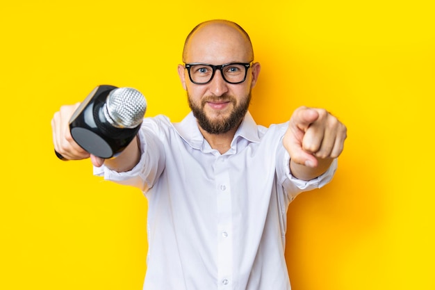 Photo jeune homme chantant avec un microphone pointe devant lui sur fond jaune