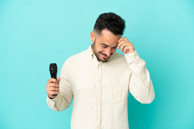 Jeune homme chanteur caucasien isolé sur fond bleu en riant