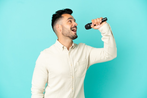 Jeune homme chanteur caucasien isolé sur fond bleu