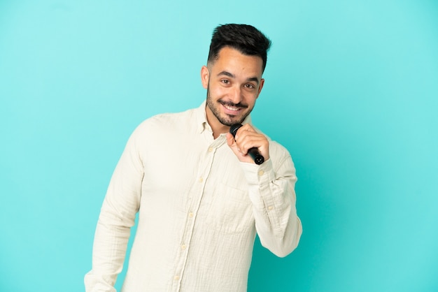 Jeune homme chanteur caucasien isolé sur fond bleu