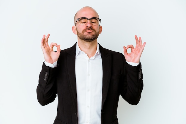 Jeune homme chauve caucasien sur bleu se détend après une dure journée de travail, elle effectue le yoga.