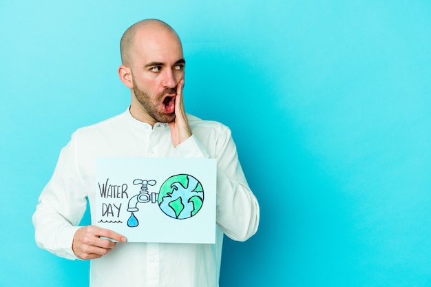 Jeune homme chauve caucasien célébrant la journée mondiale de l'eau isolée sur fond bleu