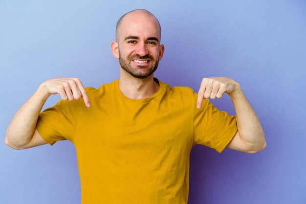 Photo jeune homme chauve isolé mur pointe vers le bas avec les doigts, sentiment positif