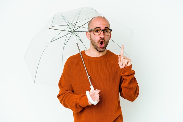 Jeune homme chauve tenant un parapluie isolé ayant une bonne idée