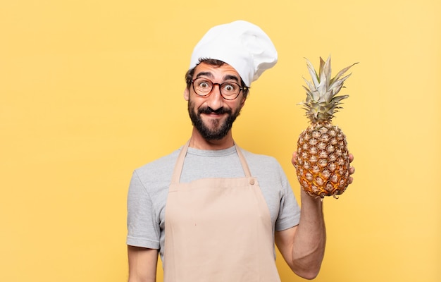 Jeune homme chef barbu expression heureuse tenant un ananas