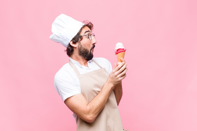 Jeune homme chef fou avec une glace contre le mur rose