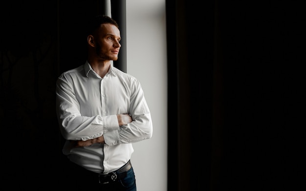 Un jeune homme en chemise blanche regarde le côté gauche de la fenêtre. photo de haute qualité