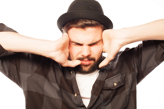 Jeune homme avec chemise carrés coning ses oreilles avec ses mains. Isolé sur blanc.