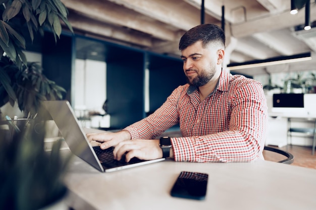 Jeune homme en chemise décontractée travaillant sur ordinateur au bureau