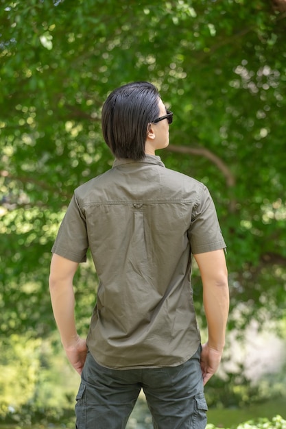 Jeune homme en chemise à manches courtes et pantalon debout dans le parc