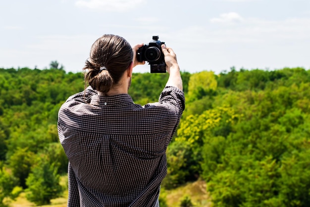 Jeune homme en chemise prenant une photo de selfie sur une photo extérieure à la lumière du jour d'été