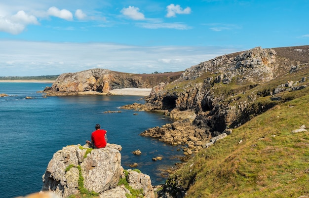 Photo un jeune homme en chemise rouge sur la côte profitant de l'été au château de dinan sur la presqu'île de crozon en bretagne française, france