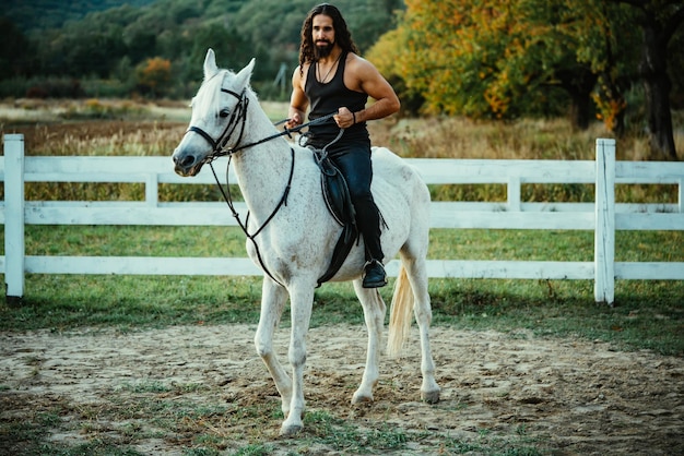 Jeune homme à cheval Beau cow-boy macho à cheval sur un cheval