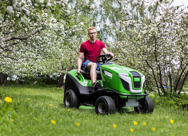 Photo un jeune homme à cheval sur une tondeuse à gazon dans un champ herbeux