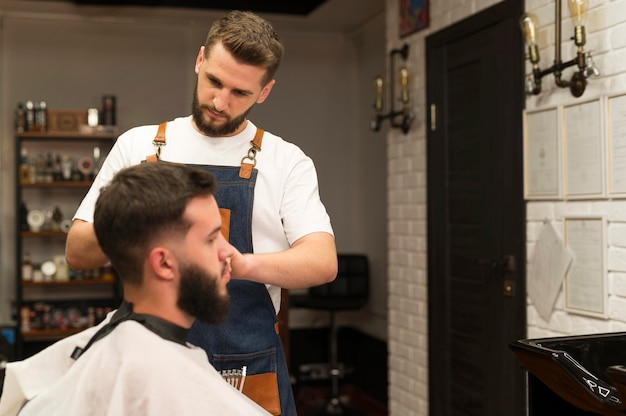 Photo jeune homme chez le coiffeur se faisant couper les cheveux